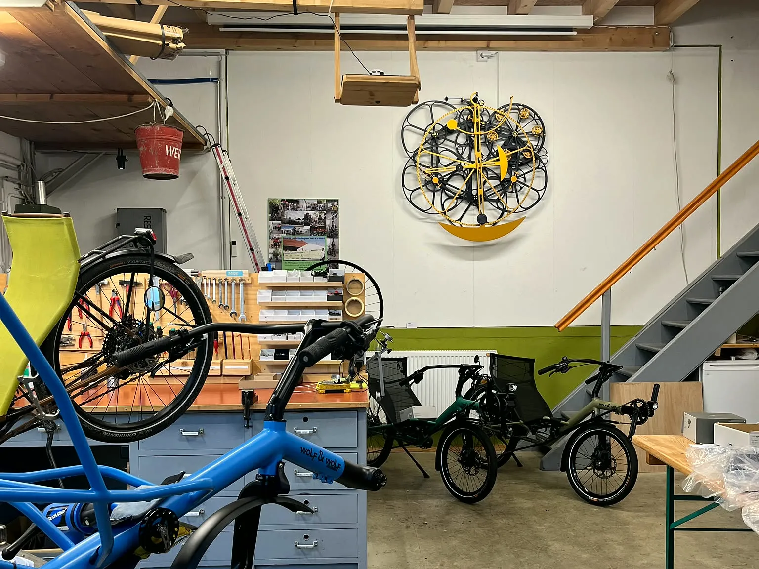 Werkstatt Lauchringen mit Rad-Kunstwerk an der Wand, Treppe und Werkbank